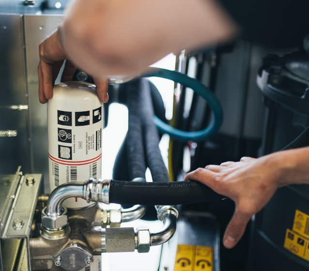 Der Ölfilter eines Atlas Copco Schraubenkompressors wird gewechselt.